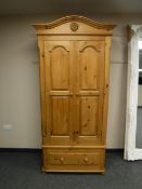 A pine double door wardrobe fitted with a drawer