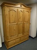 A pine double door wardrobe fitted with two drawers