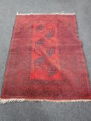 A fringed Persian rug of geometric design on red ground