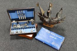 A wooden model of a three masted galleon on stand together with a box containing stainless steel