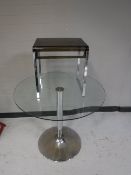 A circular glass topped pedestal table and a contemporary stool