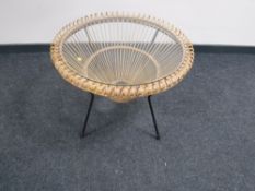 A circular wicker glass topped coffee table on metal base