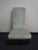 An antique bedroom chair upholstered in green floral fabric on turned legs