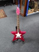 A Daisy Rock pink star electric guitar on stand
