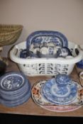 A basket of blue and white willow pattern tea and dinner ware,