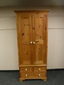 A pine double door wardrobe fitted with three drawers beneath