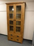 A contemporary oak double door glazed bookcase fitted with two drawers