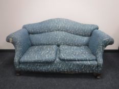 A late Victorian scroll arm settee upholstered in a purple and gold fabric on claw and ball feet