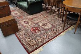 A machine made fringed eastern carpet on red ground 390 cm x 300 cm