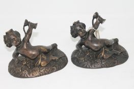 A pair of bronze figures of reclining cherubs holding goblets