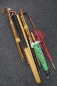 Two bundles of assorted walking sticks and canes together with a large wall fan and oriental
