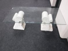 A glass topped coffee table on stone pedestals