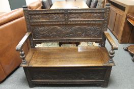 An early twentieth century carved oak monk's bench, width 117 cm.