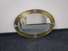 An antique oval brass framed bevelled mirror