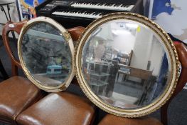 Two circular cream and gilt bevelled mirrors