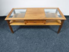 A teak glass topped coffee table fitted with a drawer