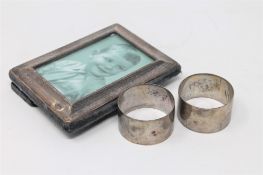 Two silver napkin rings together with a silver photograph frame