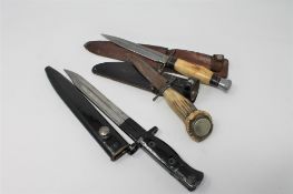 A World War II bayonet together with two hunting knives in sheathes