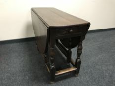 An antique oak gate leg table fitted a drawer