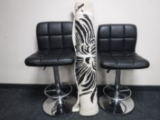 A pair of black leather bar stools and a rug