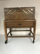 An oak concertina sewing trolley fitted with a drawer