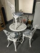 A cast metal circular garden table with four chairs,