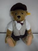 A Steiff brown mohair bear wearing glasses and a hat, signed to the foot, length 35 cm.
