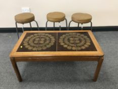 A teak tiled topped coffee table and three leather topped stools