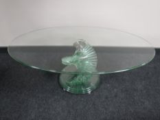 An oval all glass coffee table on spiral base