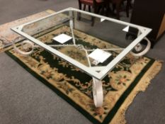 A large glass topped coffee table on a wrought iron base