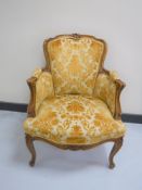 A carved walnut salon armchair upholstered in a gold brocade
