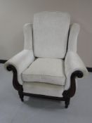 A wing back armchair upholstered in cream fabric