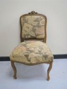 An antique carved walnut dressing table chair upholstered in a floral fabric