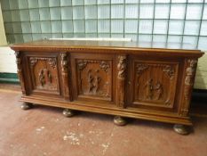 A heavily carved oak continental triple door sideboard on bun feet