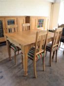 A blonde oak dining table and four rail back chairs