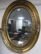 A late 19th century ornate oval gilt framed mirror