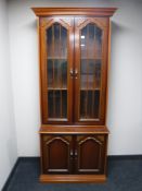 A contemporary glazed door bookcase fitted cupboards beneath