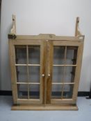 A stripped pine kitchen glazed door wall cabinet
