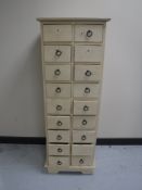 A narrow painted hardwood nineteen drawer chest