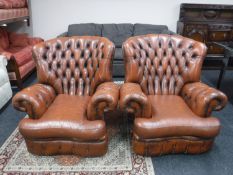 A pair of brown leather Chesterfield armchairs