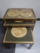 A nest of three mahogany brass topped tables depicting maps