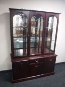 A triple door display cabinet fitted with cupboards and drawers beneath in a mahogany finish