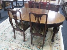 An oval mahogany wind out table with winder and leaf plus four dining chairs