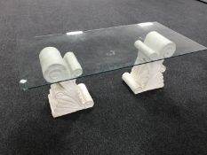 A glass topped coffee table on stone pedestals