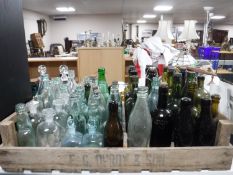 A wooden fruit crate containing a collection of antique glass bottles