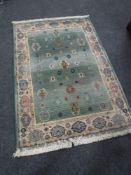 A contemporary fringed woollen rug on green ground