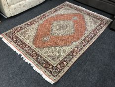 A fringed Persian Tabriz design rug on red ground