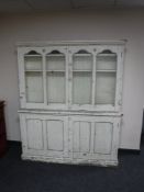 An antique painted bookcase fitted cupboards beneath