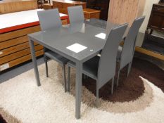 A contemporary metal glass topped dining table and four grey leather chairs