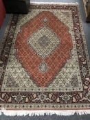 A fringed Persian Tabriz design rug on red ground